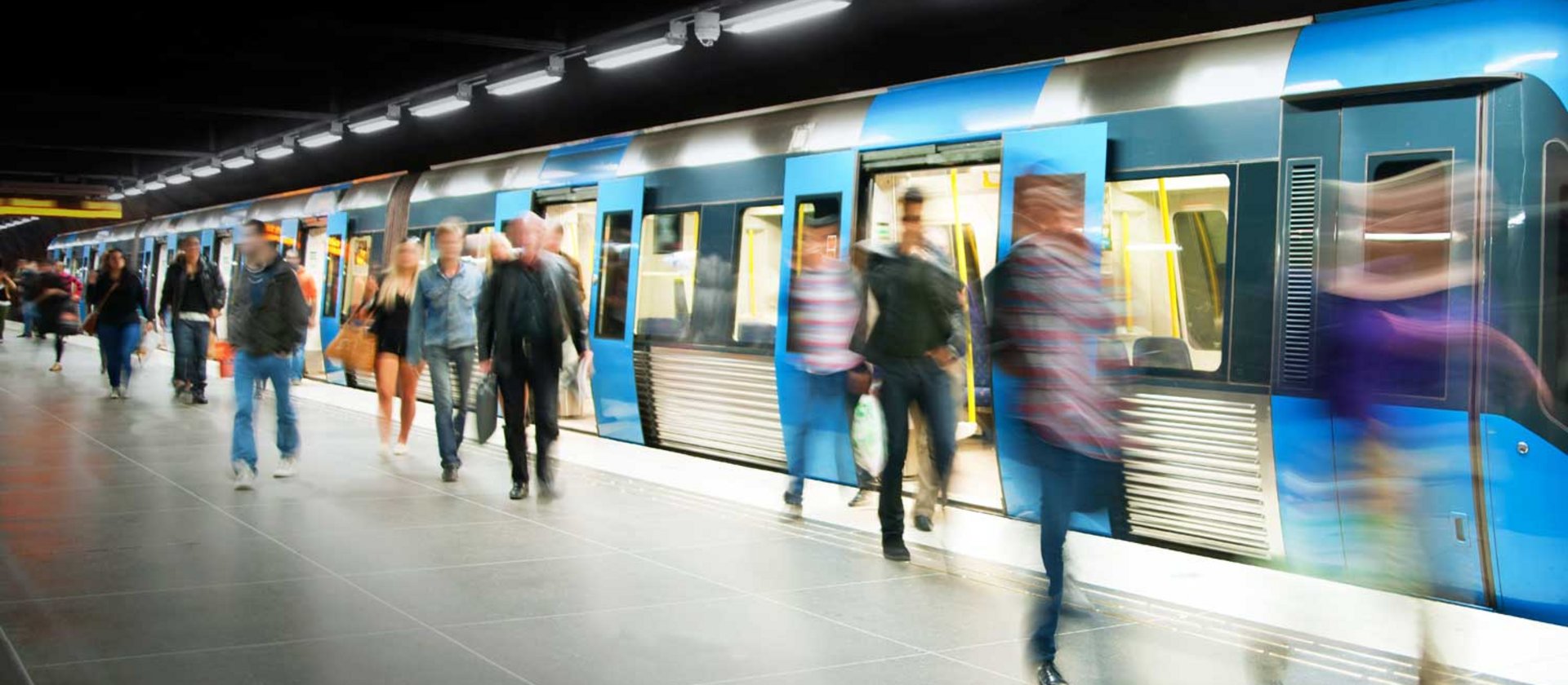 Metro passengers boarding train at busy station platform