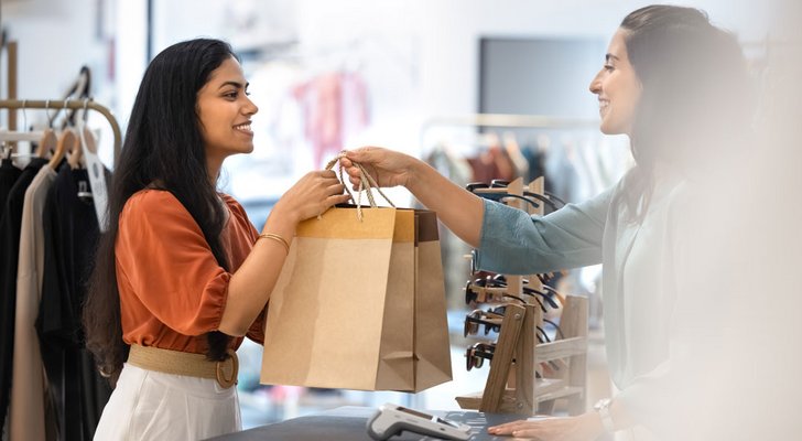 Retail customer receiving shopping bags from store associate at checkout