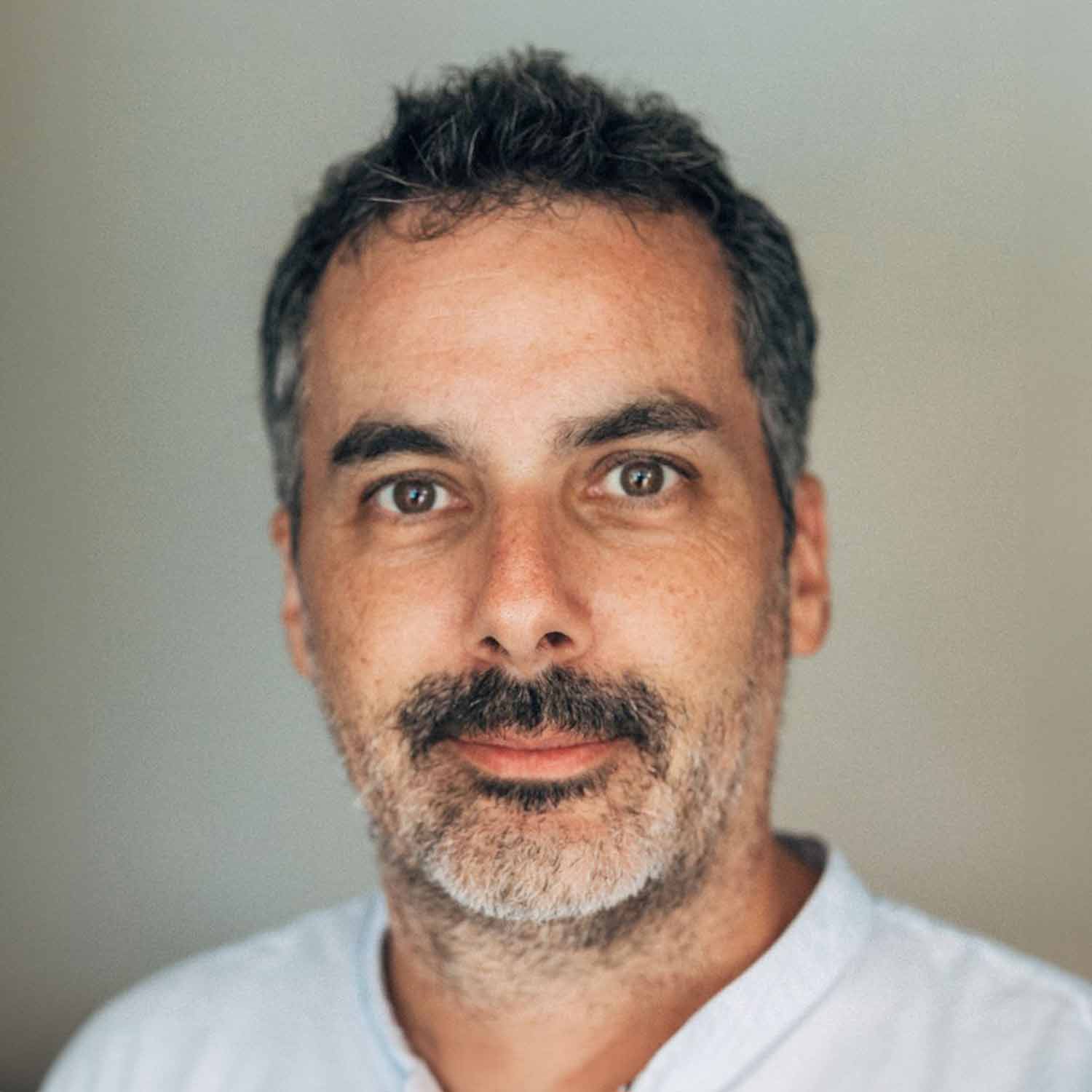 Man with salt-and-pepper hair, mustache and beard, neutral expression, casual shirt
