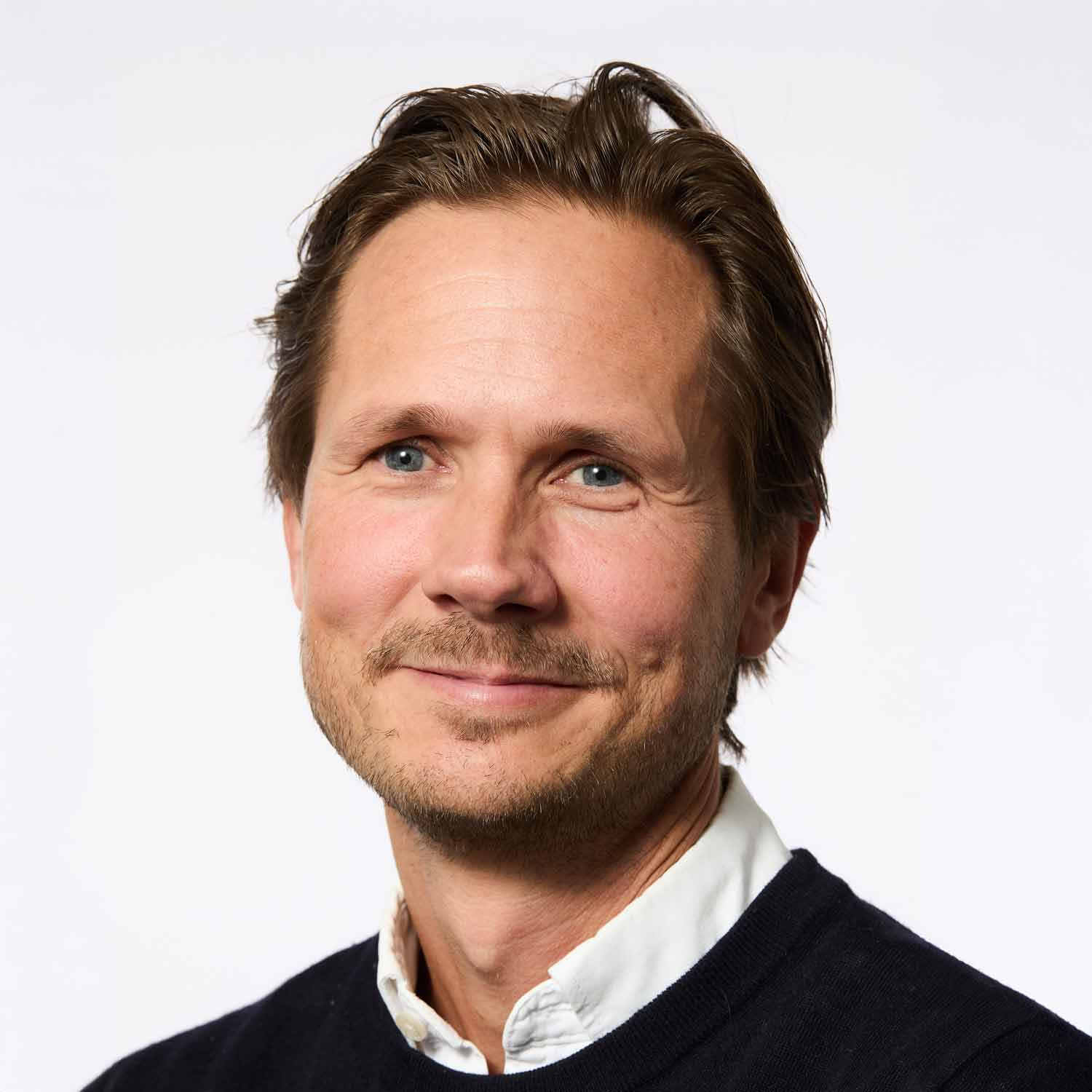 Light-haired man with blue eyes, slight stubble, gentle smile, casual style